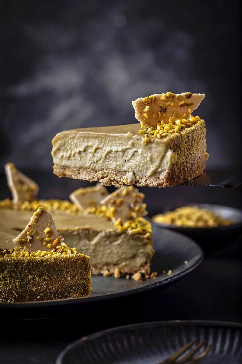 Torta de pistache da Cacau Vanilla com uma fatia servida em primeiro plano