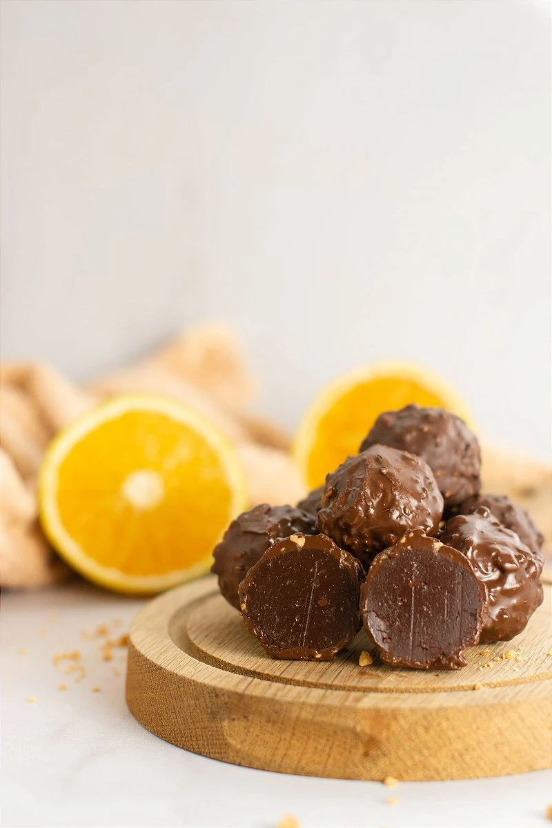 Trufas de chocolate crocante de laranja em uma base de madeira com laranja ao fundo